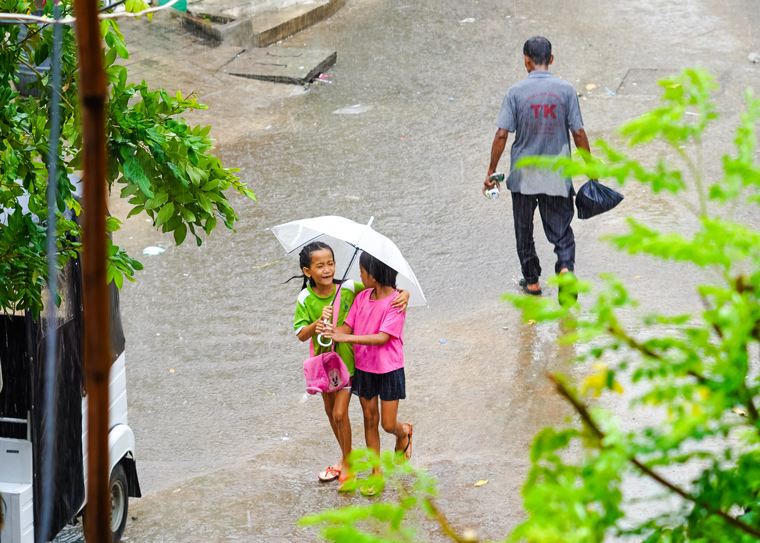 young girls share umbrella in cambodia